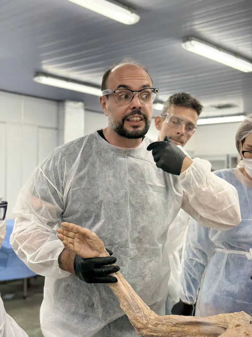 Professor mostrando um braço dissecado aos alunos